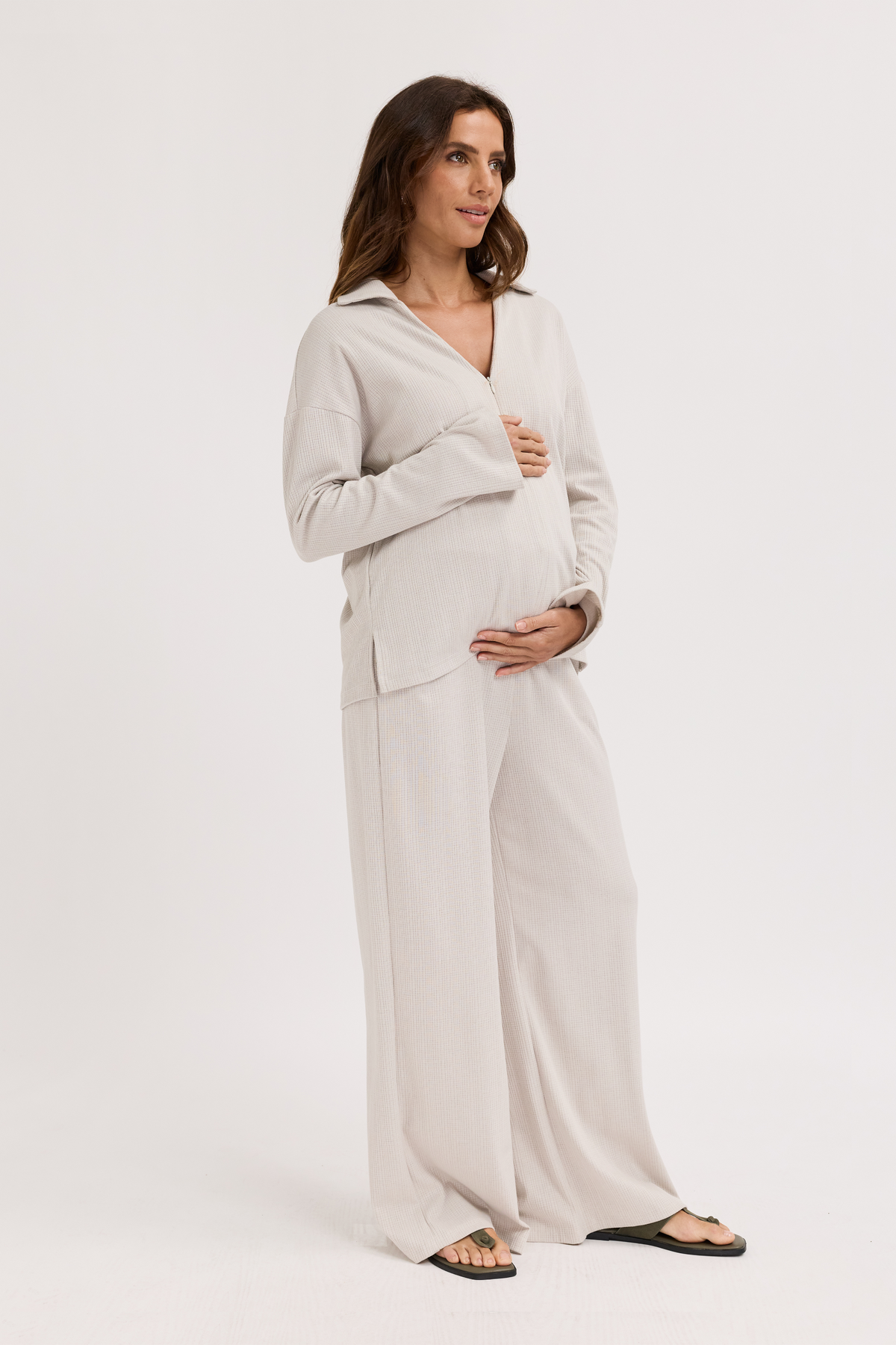 Pregnant Woman wearing a light gray outfit on a white background