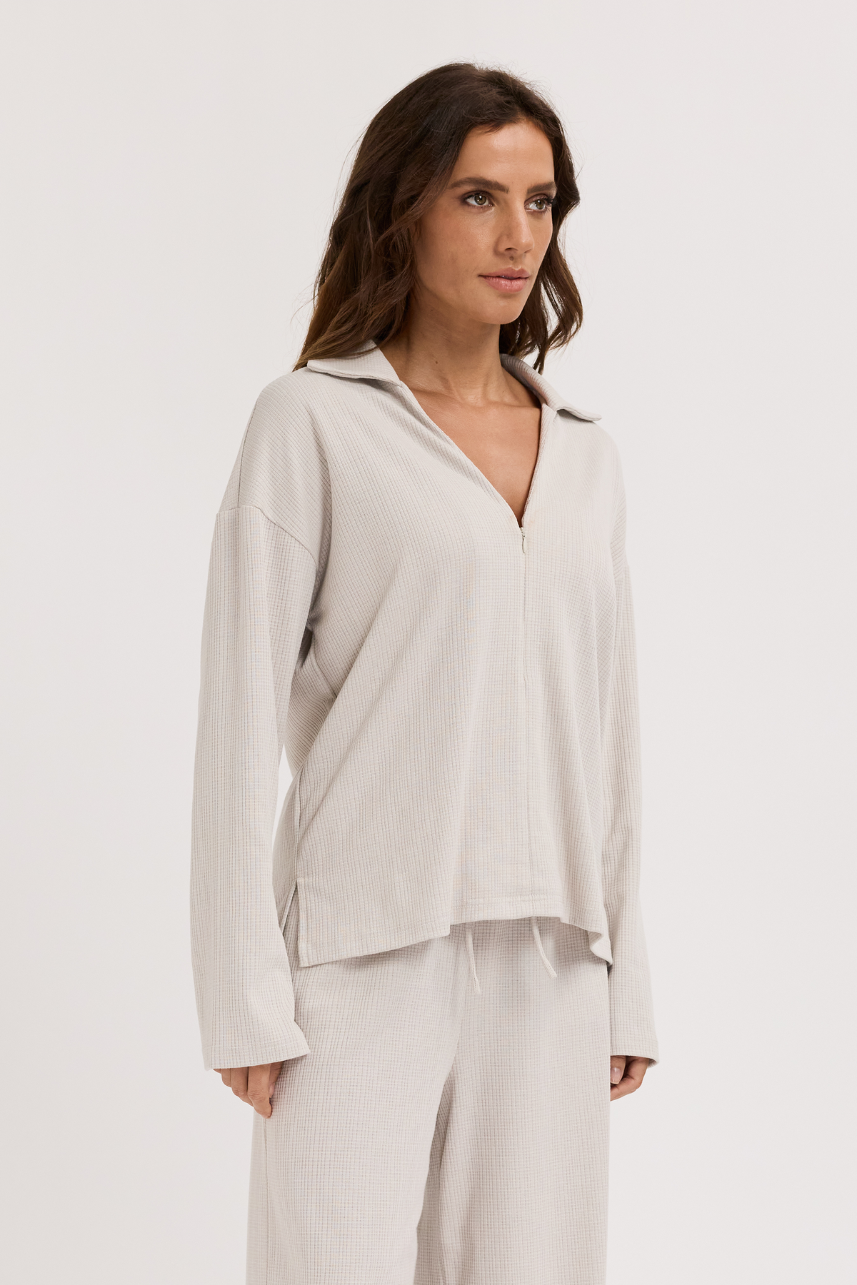 Woman wearing a light gray maternity outfit on a white background
