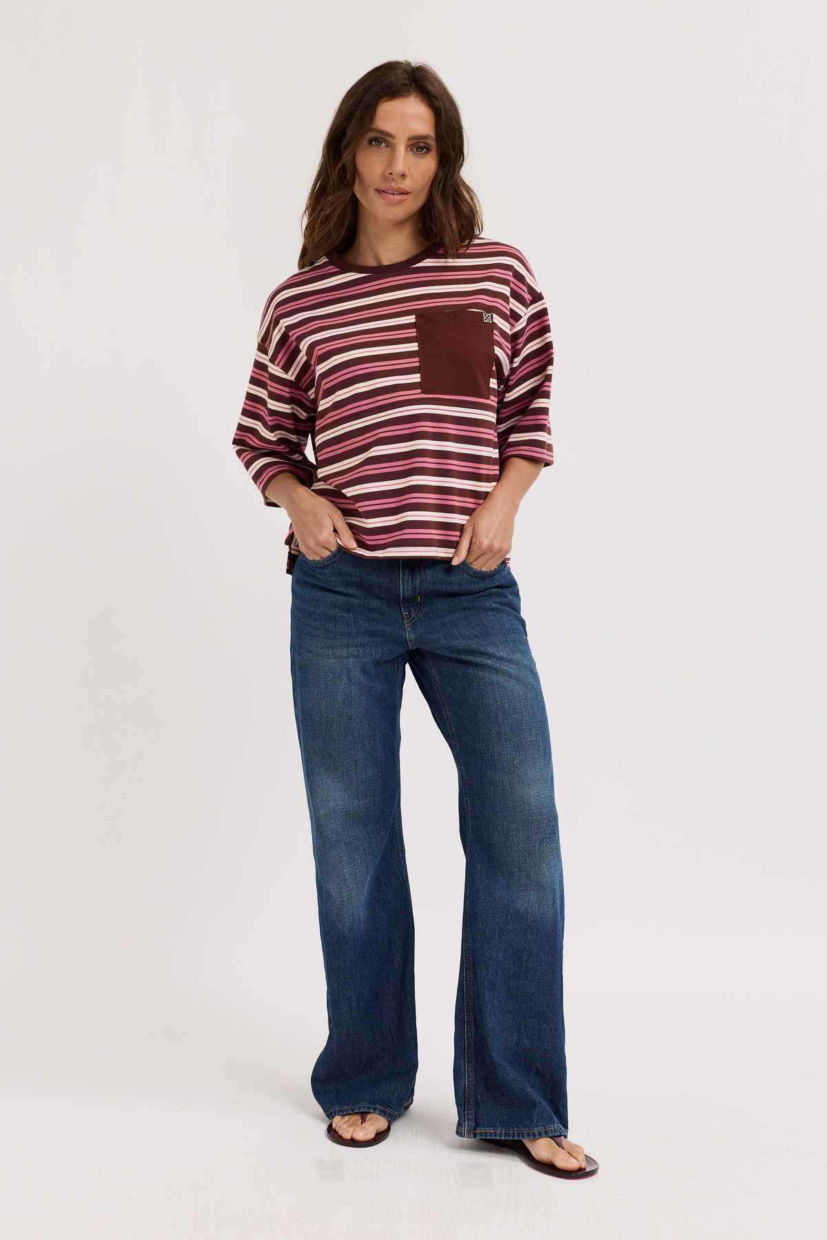 Woman wearing a striped nursing tee and blue jeans on a white background