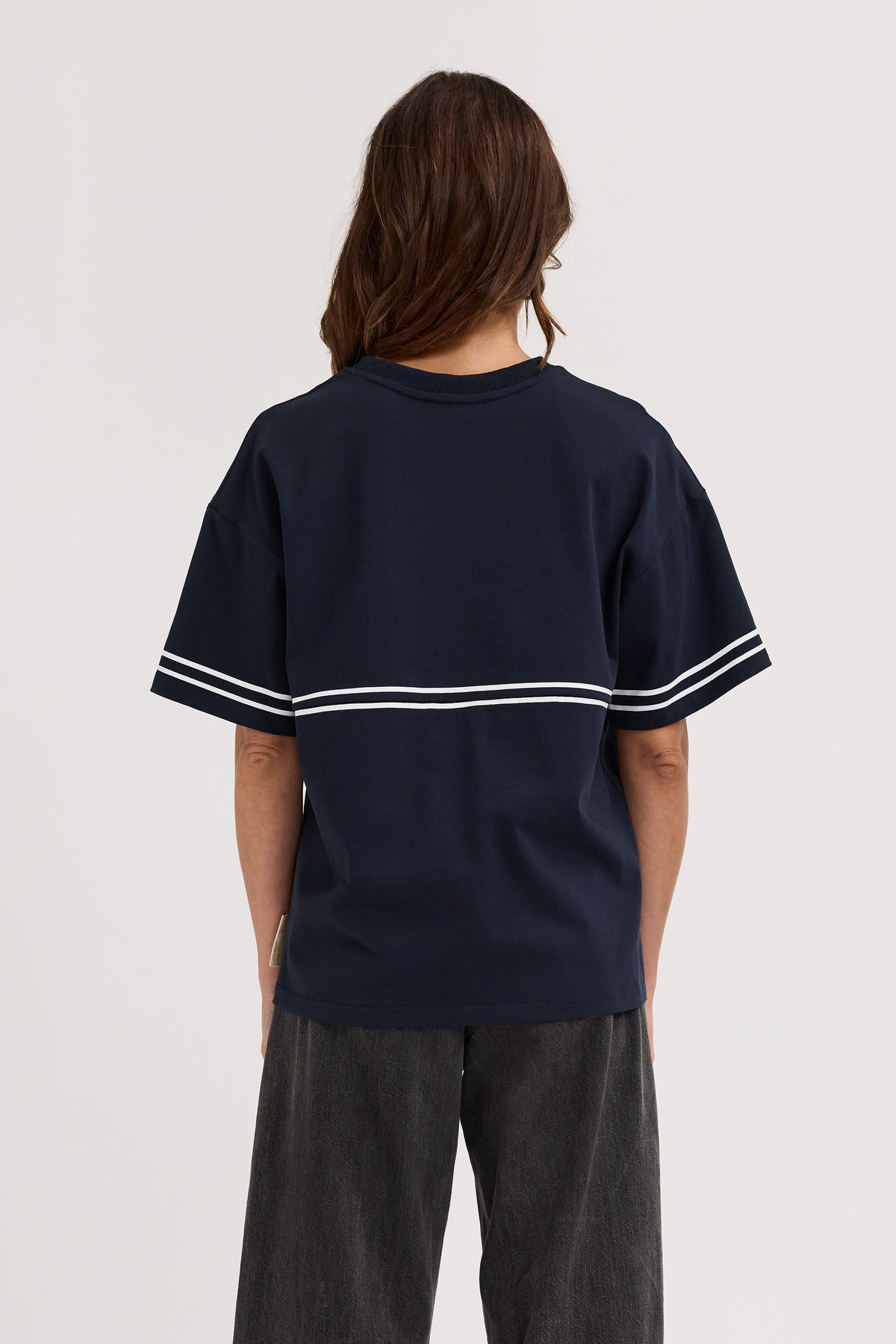 Person wearing a navy blue t-shirt with white stripes on a plain background