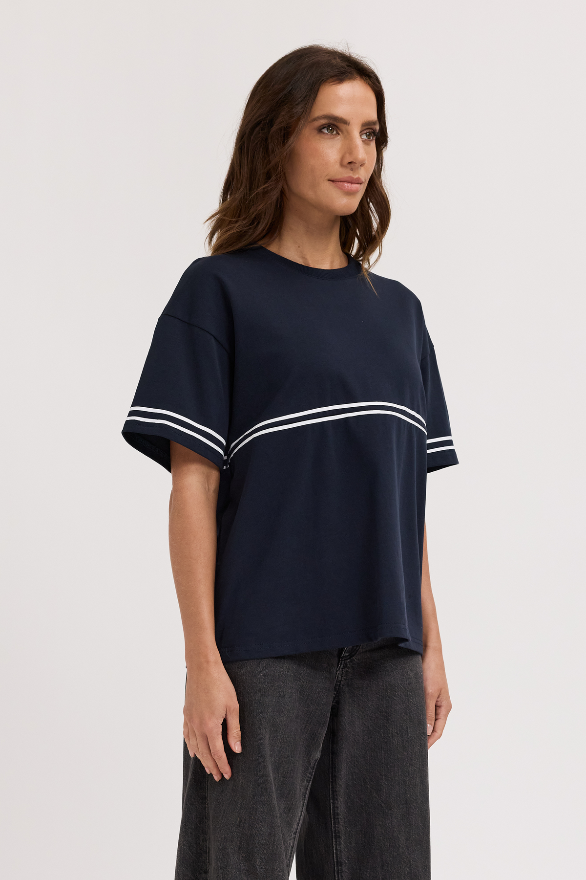 Woman wearing a navy blue t-shirt with white stripes on a plain background