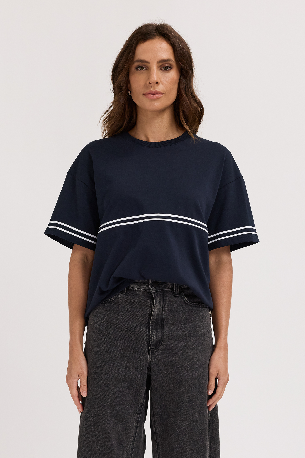 Woman wearing a navy blue t-shirt with white stripes on a plain background