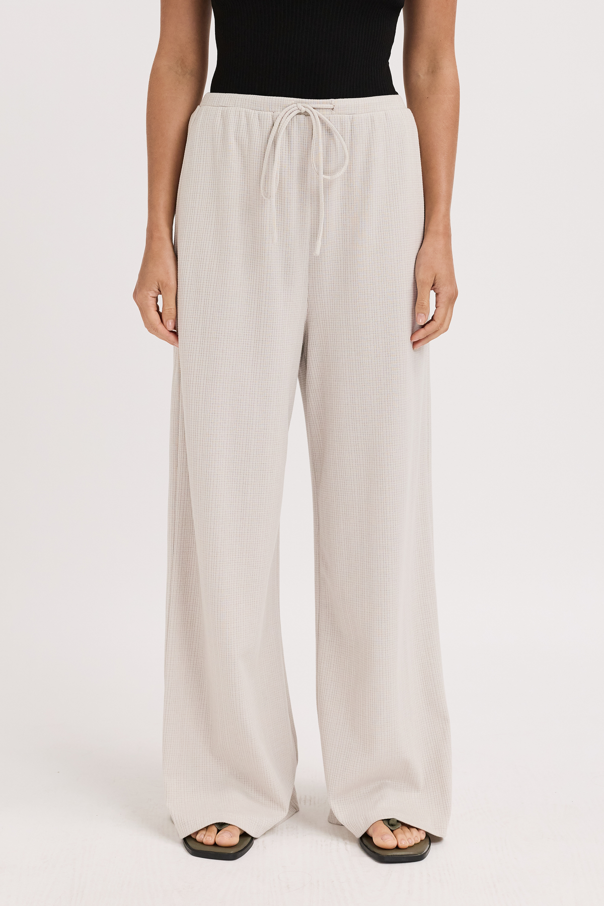 Beige wide-leg pants worn by a person on a white background