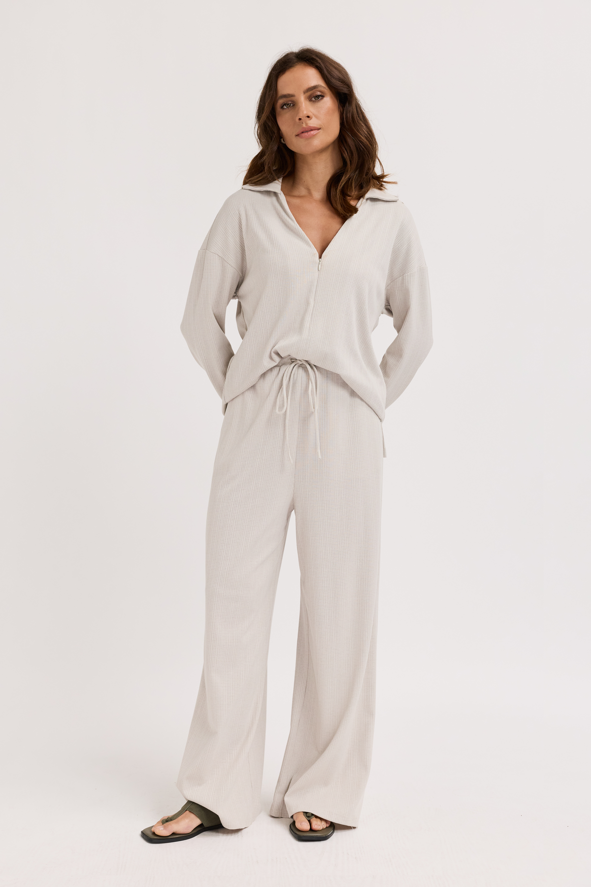 Woman wearing a light gray outfit on a white background