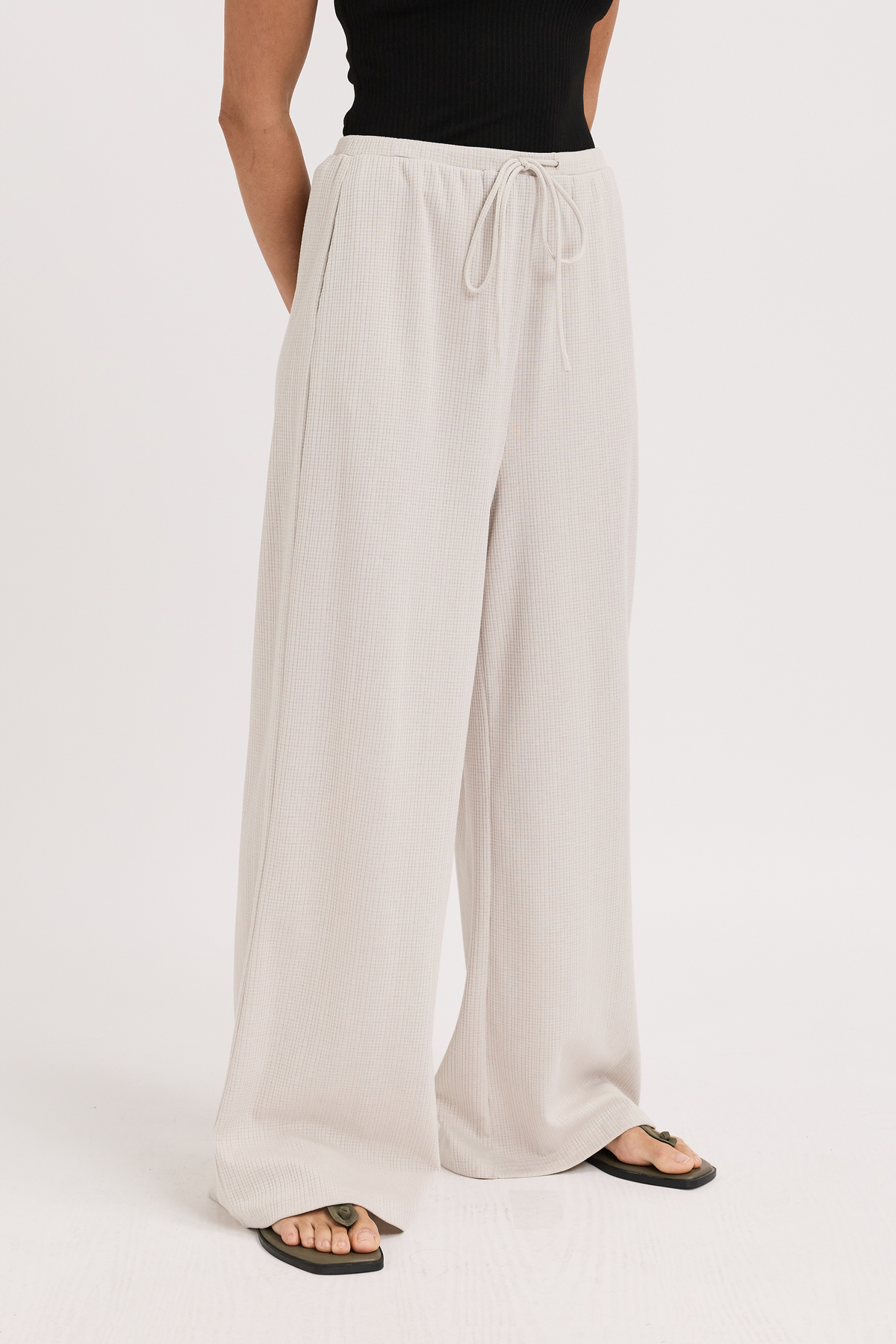 Beige wide-leg pants worn by a person on a white background