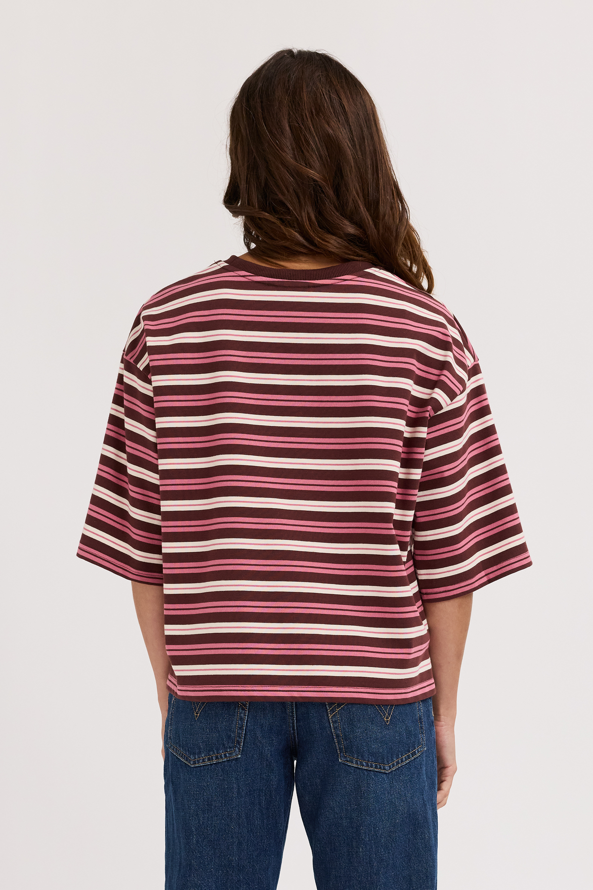 Mother wearing a striped shirt and jeans on a plain background