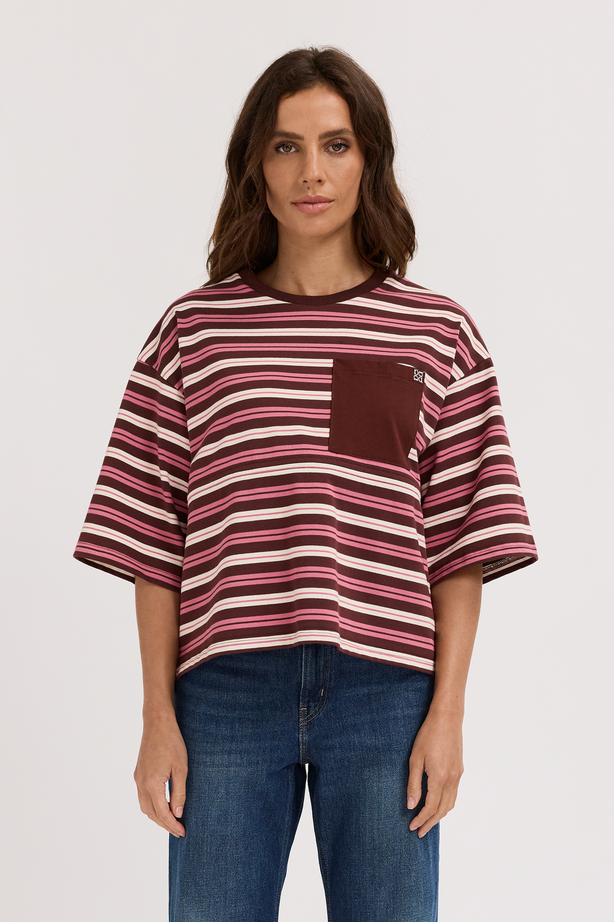Woman wearing a striped breastfeeding shirt with a pocket on a plain background