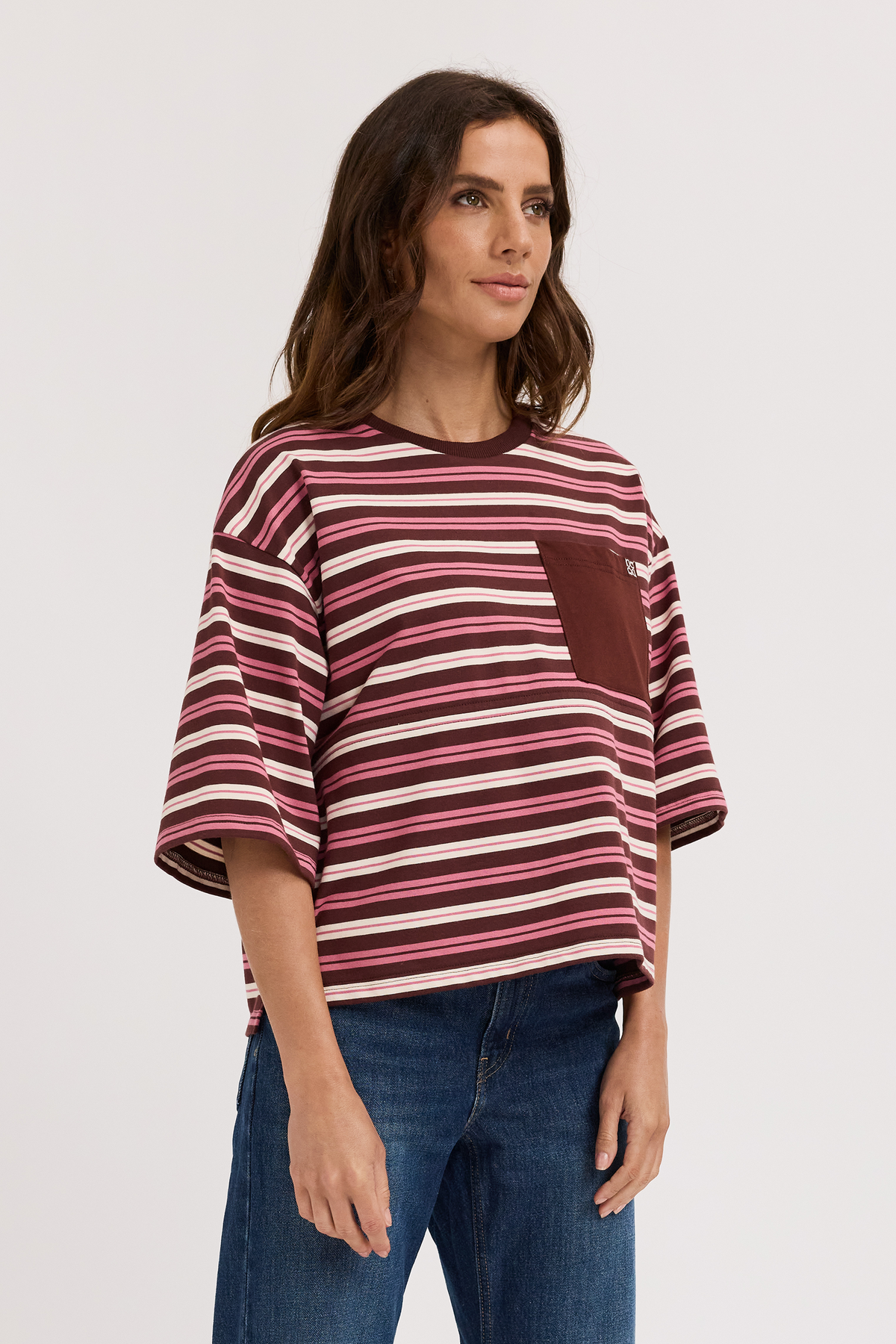 Woman wearing a burgundy striped nursing shirt with a pocket on a white background